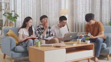 asian teen group studying at home. helping each other doing project, a boy in plaid shirt thinking, raising index finger, sharing idea with friends, writing into notebook and typing on a laptop