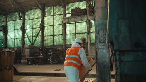 A-man-with-Black-skin-in-a-white-uniform-and-an-orange-vest-with-a-white-helmet-picks-up-waste-paper-that-a-colleague-gives-him-from-the-trunk-of-a-truck-during-unloading-at-a-waste-processing-plant