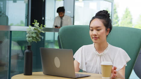 Mujer-De-Negocios-Utilizando-Un-Ordenador-Portátil-Trabajando-En-La-Mesa-En-La-Zona-De-Descanso-Del-Edificio-De-Oficinas