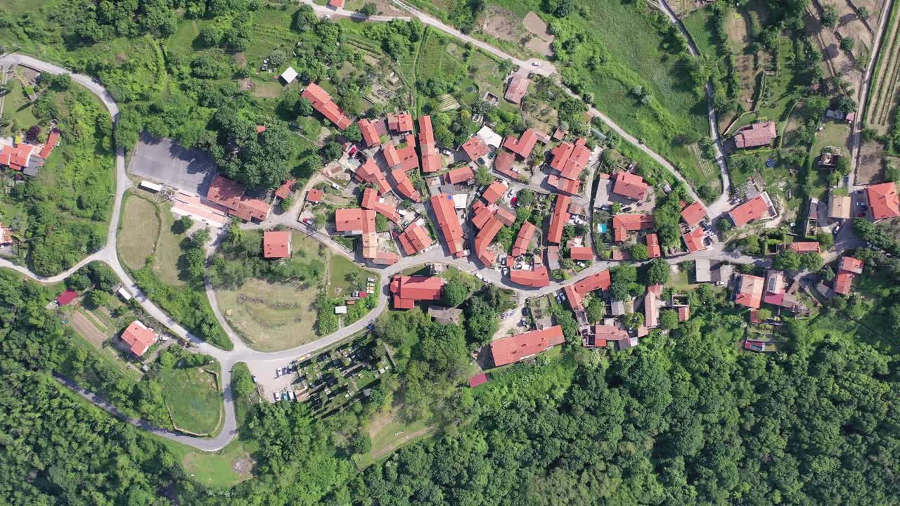 Aerial view of a village with red-roofed houses surrounded by forest