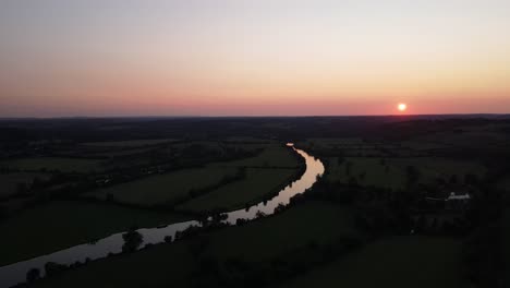 River-Thames-with-bright-golden-sun-over-horizon-and-colored-sky-at-sunset,-Mapledurham-in-UK