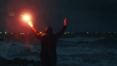 hombre saludando con una torcha de señal de carretera para pedir ayuda en una tormenta