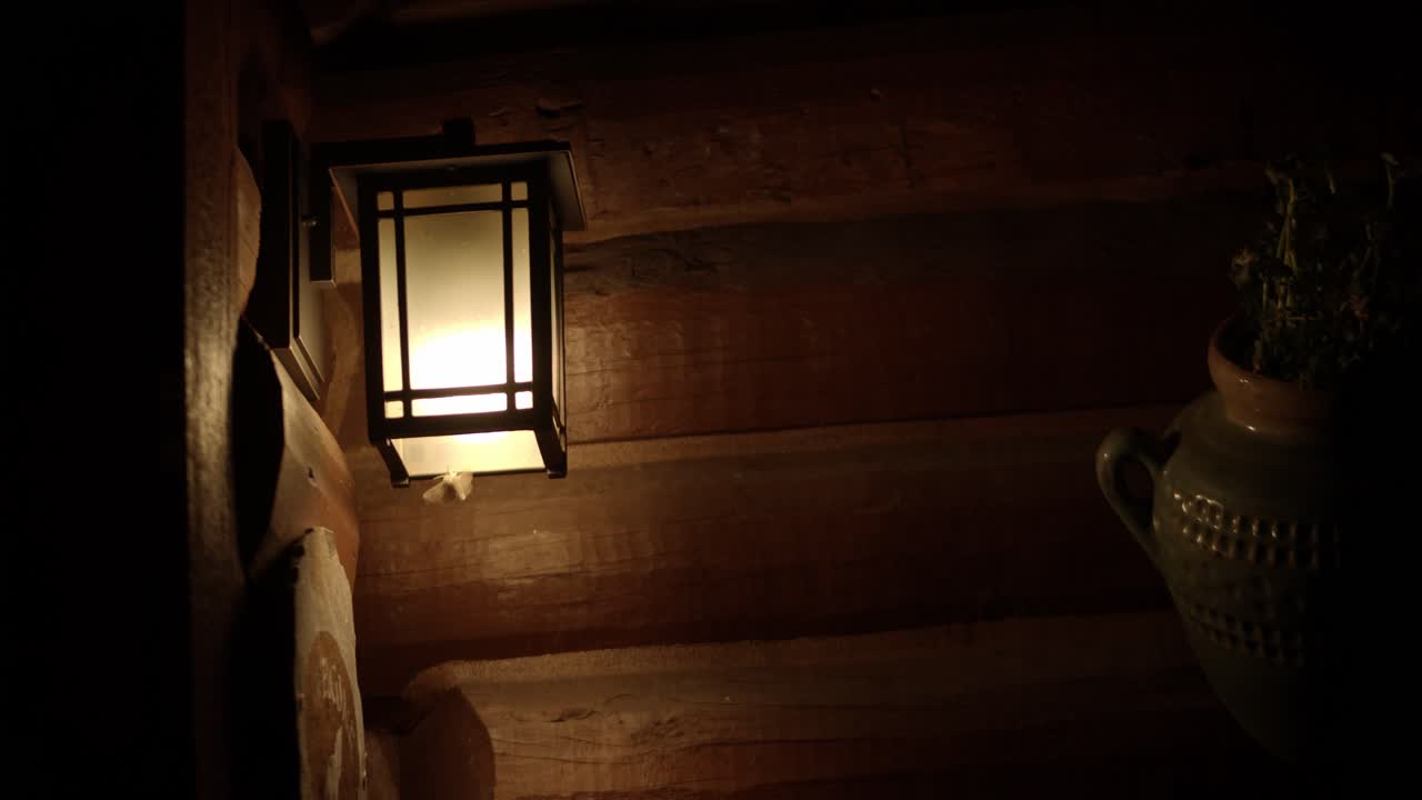 나방은 통나무 집의 현관 조명 주위를 날아다닌다