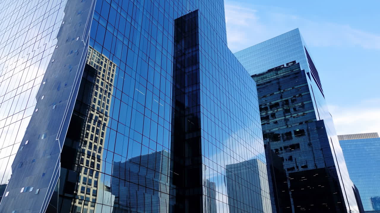 Panorâmica Ascendente de Arranha-céus Modernos de Vidro Contra o Céu Azul