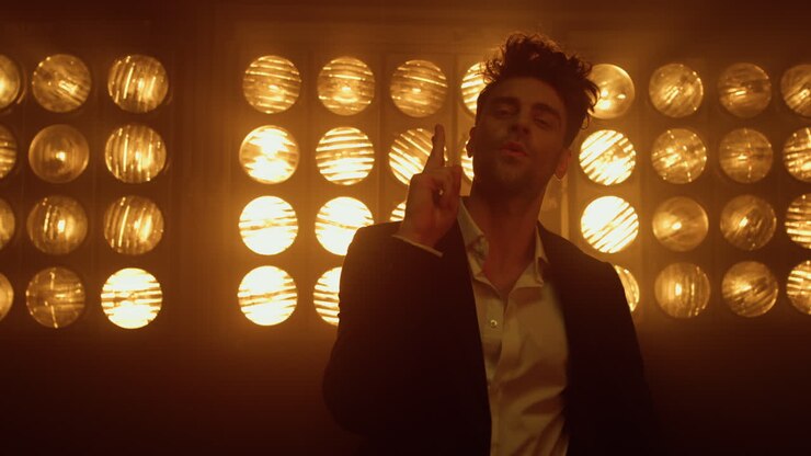 Ragazzo seducente che posa schioccando le dita in un night club, primo piano. Modello maschile in piedi sul palco.