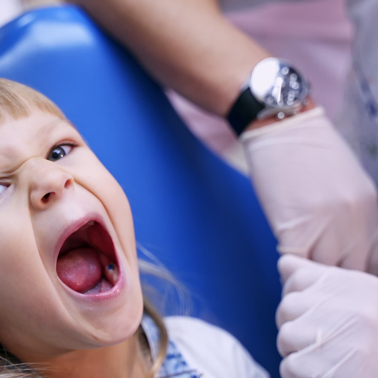 Little child in stomatology chair opens her mouth wide and shows her teeth to the doctor - close up video.