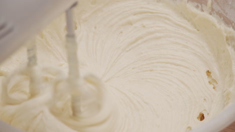 electric handheld mixer stirring cake ingredients close up, slow motion