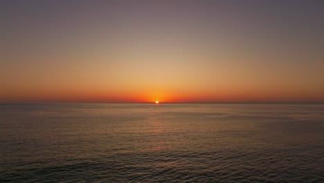 Aerial-dolly-shot-toward-the-vibrant-sunset-over-the-horizon-in-Iquique,-Chile