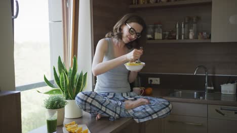 Attractive-woman-sitting-on-table-and-eating-breakfast