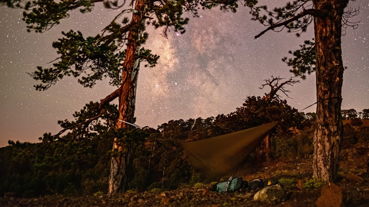 밤 에 키프로스 의 올림포스 산 을 따라 평화로운 캠핑장 에 있는 나무 들 사이 에 흔들리는 하마크 에서 잠을 자고 있는 하이커 에 대한 별 의 움직임 의 타임  ⁇ 스  ⁇