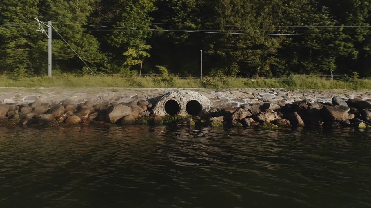 Orbiting Shot of Drainage Pipes Surrounded Rocks by the River