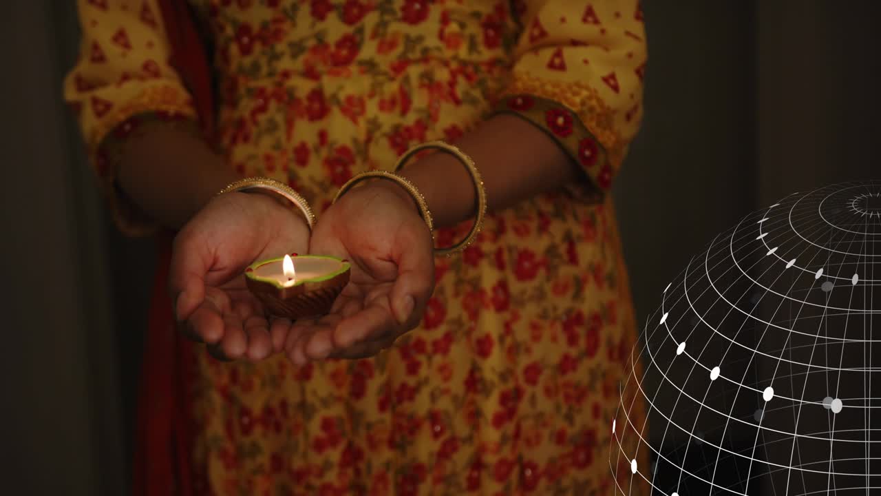 Woman holding lit diya, wire globe entering left, drifting, obscuring, revealing flame for tech