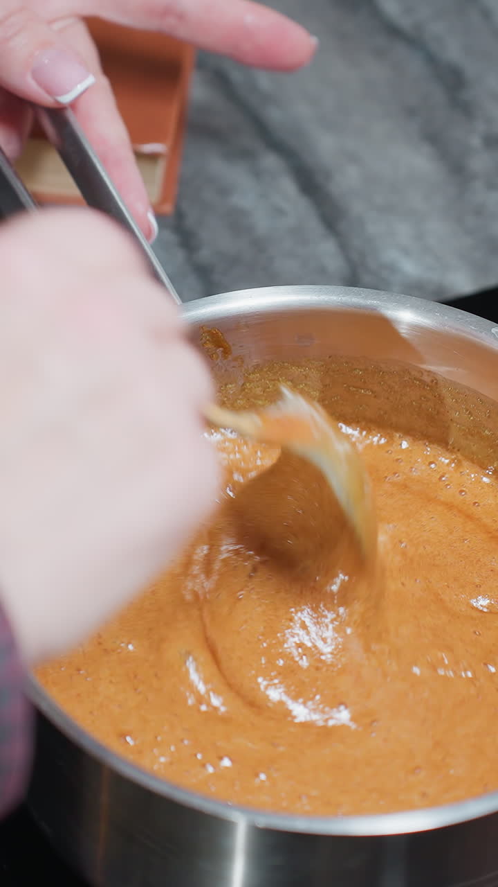 primer plano de una mujer cocinando, agitando sopa burbujeante mientras sostiene el mango de la olla en la estufa, el rico plato hirviendo mezcla ingredientes a medida que el vapor se eleva en una cocina acogedora