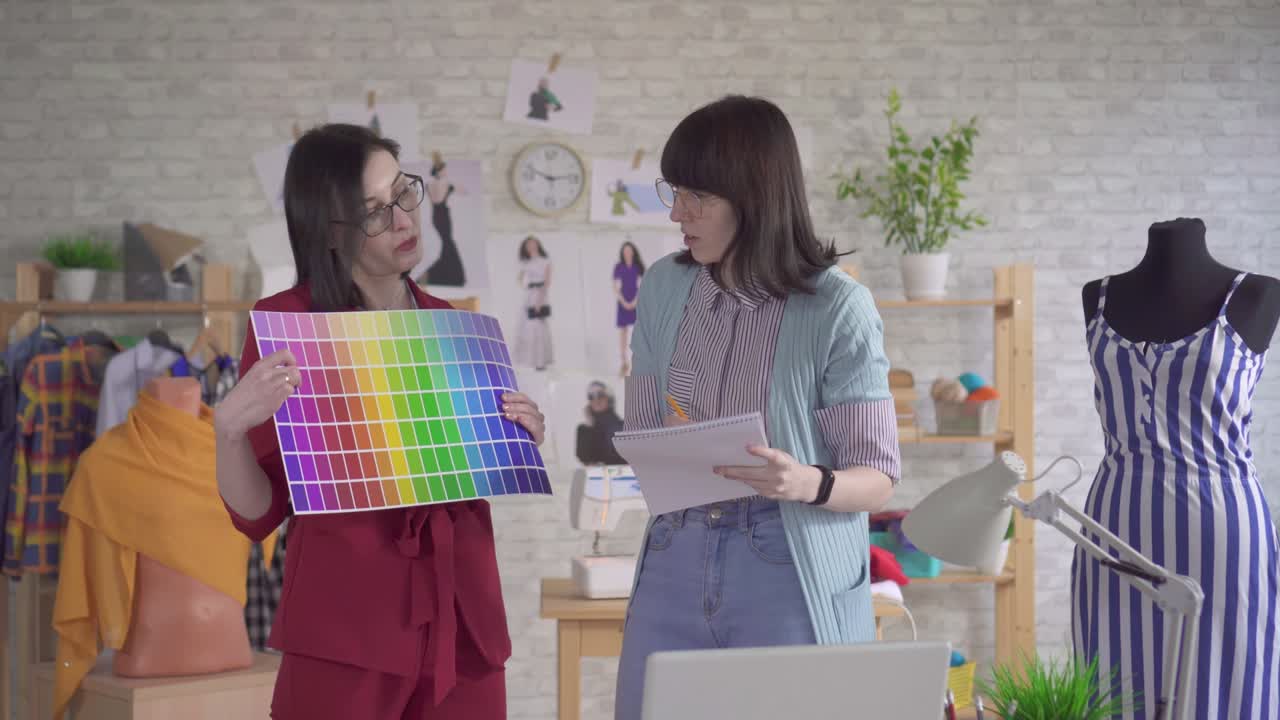 dos jóvenes diseñadores de moda a la moda trabajando en el estudio eligen un color de la paleta