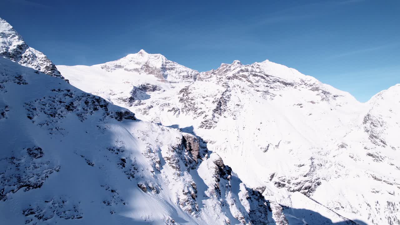 Vista aerea di un paesaggio montano innevato con foreste in una soleggiata giornata invernale ad Alp Grum, Svizzera