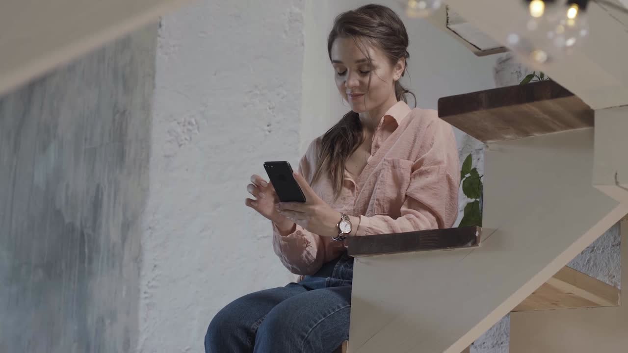 mujer usando un teléfono inteligente en las escaleras de su casa