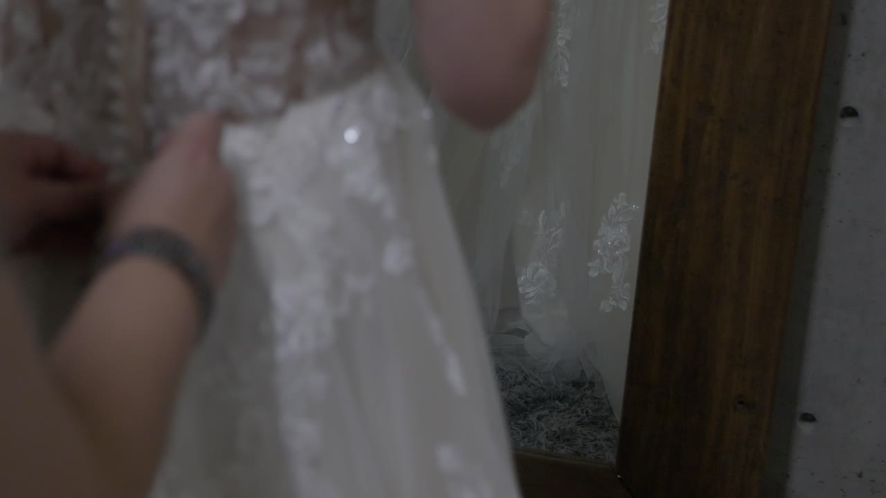Wedding Day stock clip of bride&rsquo;s dress in mirror as she&rsquo;s getting ready and friend buttons up back of dress