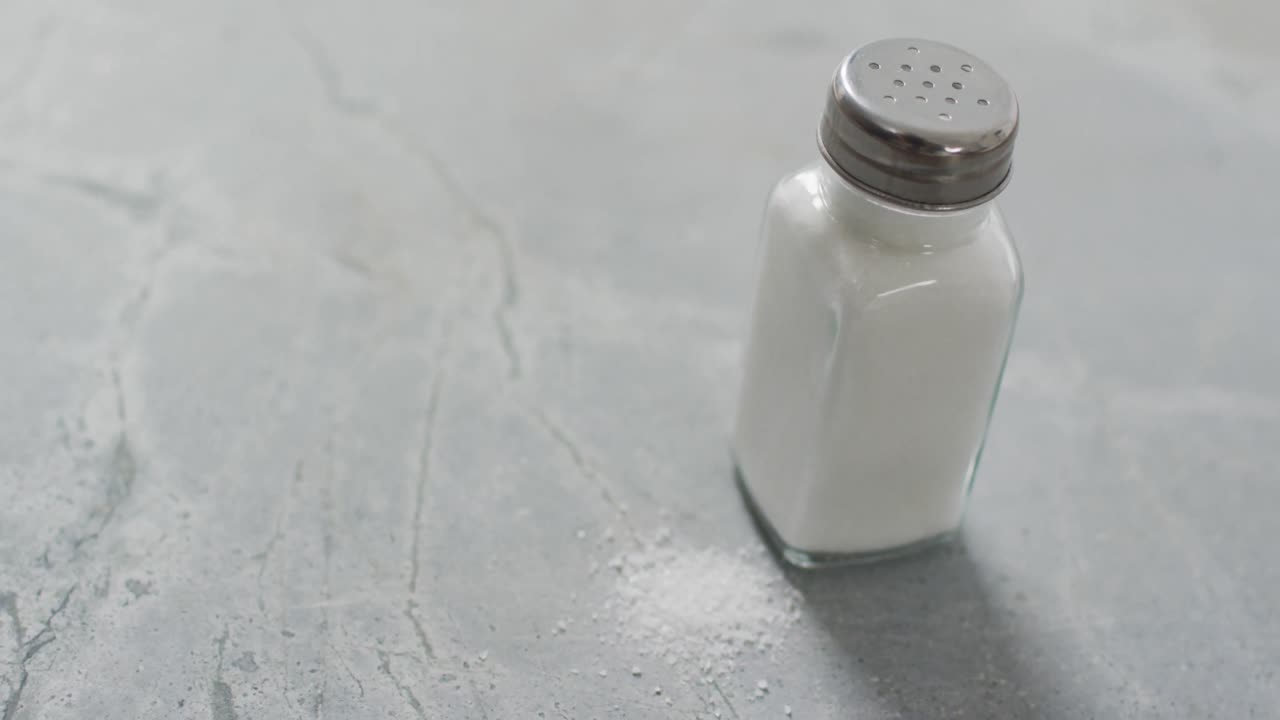 Vídeo de sal en un salero sobre encimera de cocina de piedra