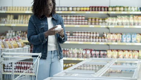 Smiling-young-customer-choosing-goods-in-freezer