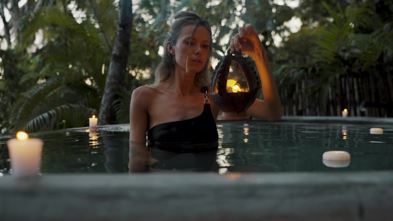 Uma mulher se inclina sobre uma piscina de spa fumegante em um retiro na selva tropical em Petén, Guatemala.