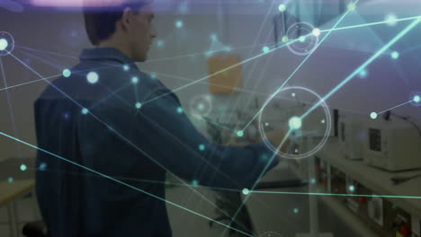 male technician adjusting control panel in electronics lab, showing digital network overlay