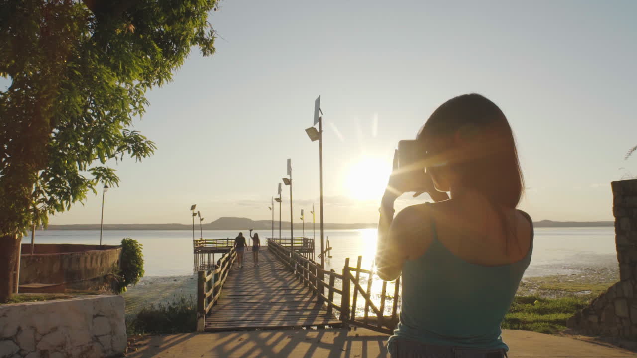 una adolescente tomando una foto de su familia caminando por el muelle en el lago ypacarai