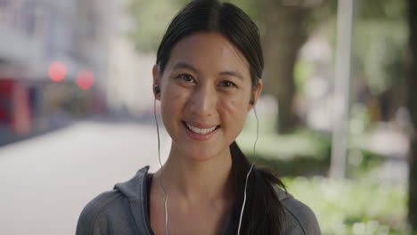 portrait-of-beautiful-asian-woman-smiling-happy-wearing-earphones-listening-to-music-enjoying-relaxed-sunny-day-in-urban-city-street-background