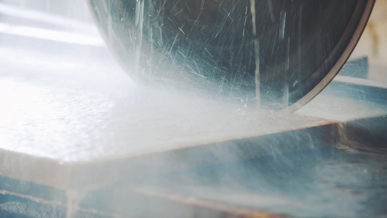 An automatic machine cuts the stone with a saw using water. Factory of natural stone