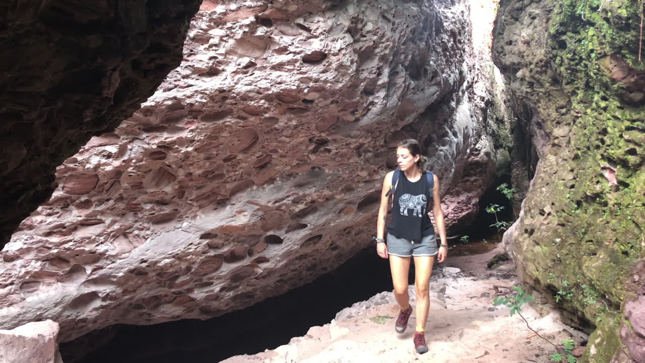 Young woman adventurer walks in cave entrance in Chapada Diamantina Brazi, slowmotion