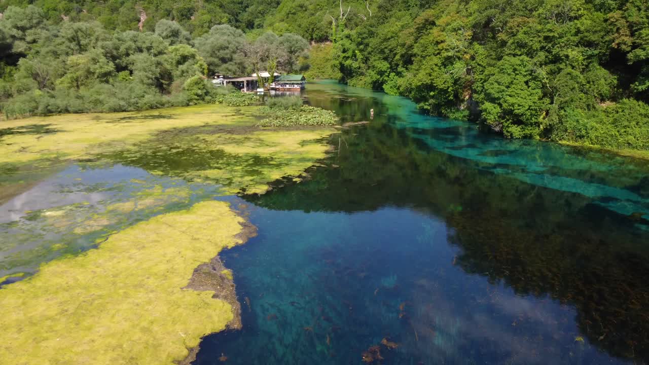 toma de dron del ojo azul en albania - dron está siguiendo el flujo del río, pasando por un restaurante al lado