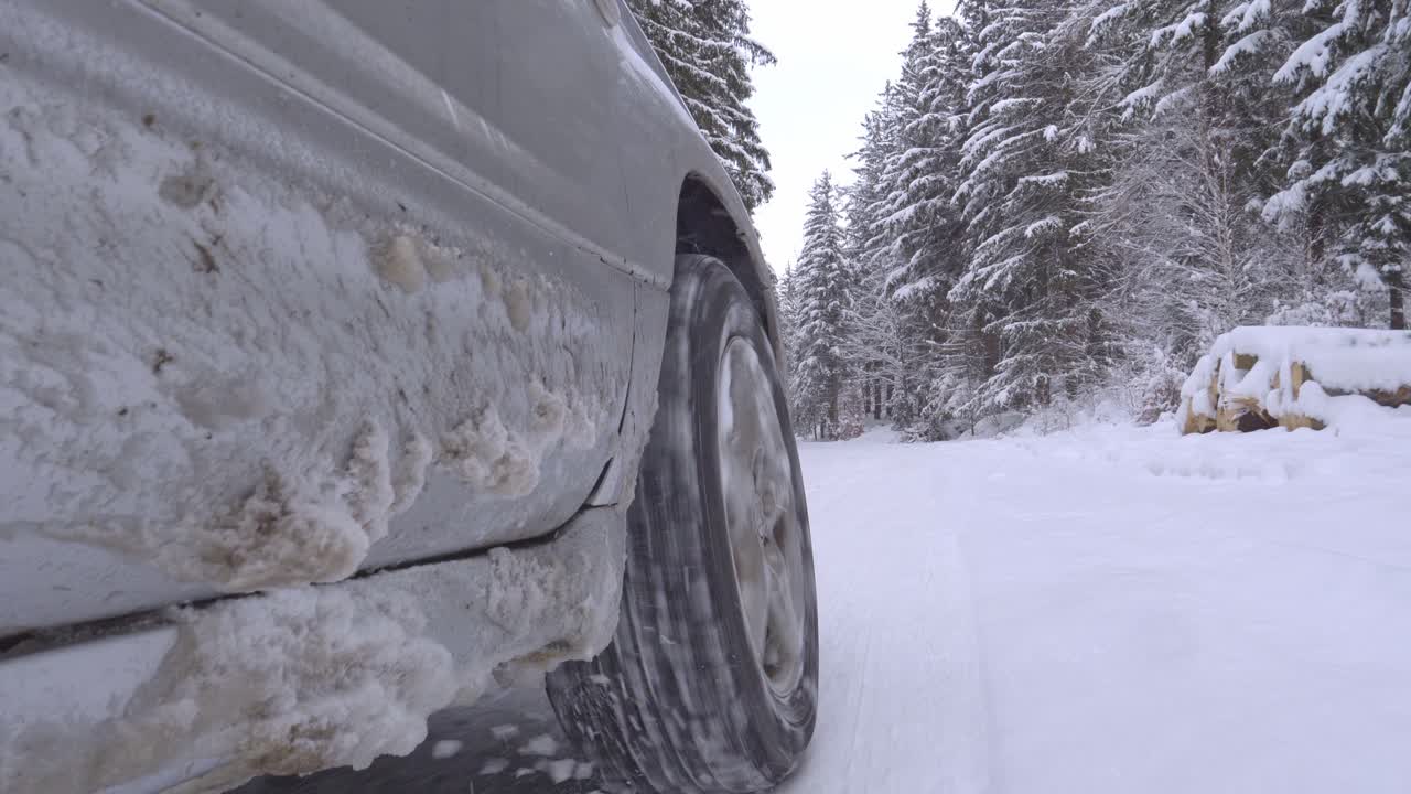 cerca de la rueda del coche conduciendo por un camino forestal nevado sin cadenas para neumáticos