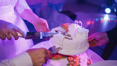 the newlyweds are cutting a wedding birthday cake. they put a piece on a plate. close-up shooting