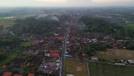 Abendliche-Luftaufnahme-Einer-Straße,-Die-Die-Stadt-Ubud-Durchquert,-Mit-Vielen-Häusern-Und-Reisplantagen-In-Der-Umgebung---Bali,-Indonesien