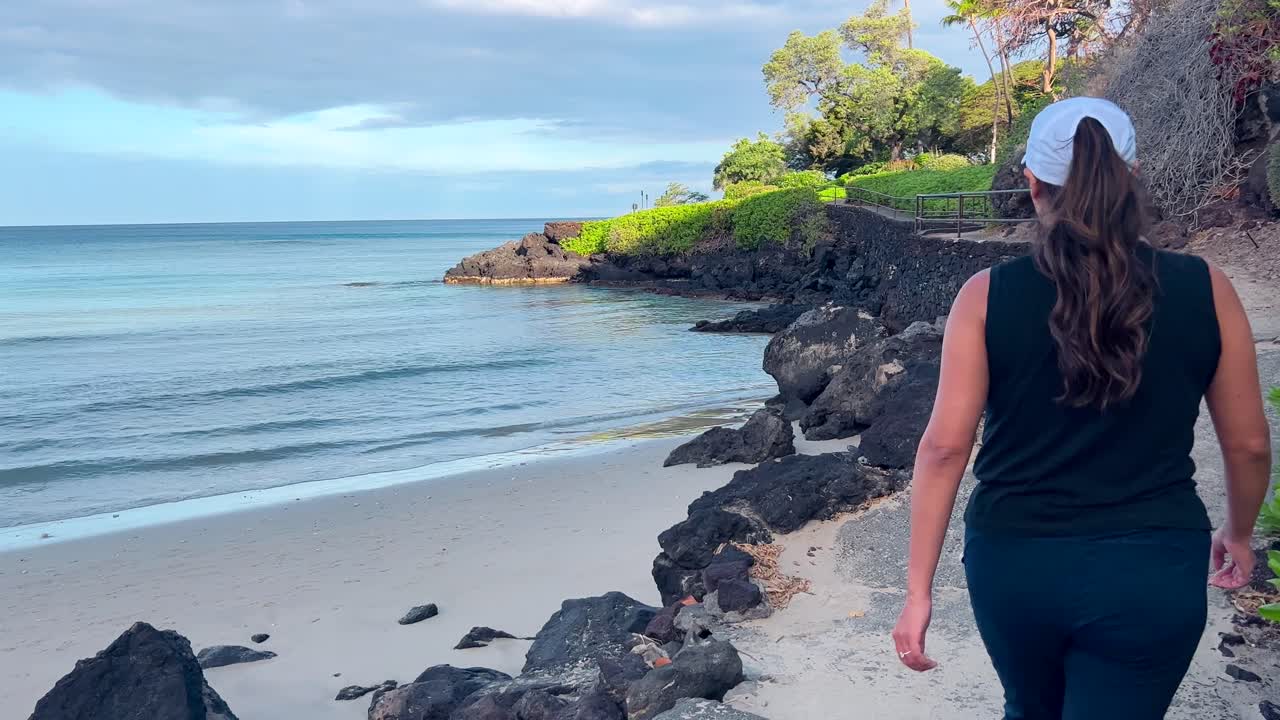 섬 낙원의 산책로에서 해변을 따라 걷는 젊은 히스패닉 여성