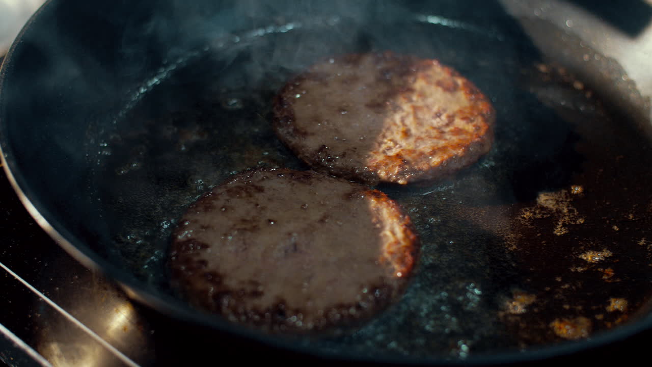 Cook putting pieces of cheese on chops frying in pan. Cooking hamburger