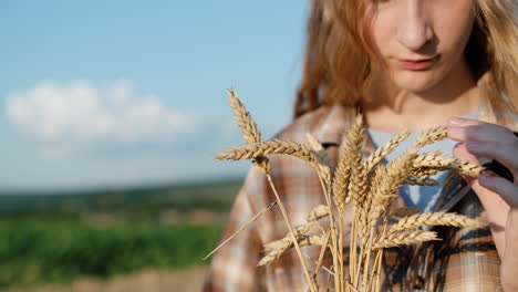 close-up portret van een tienermeisje met spikelets van tarwe in haar hand. geplaatst tegen een achtergrond van een schilderachtig platteland