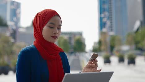 woman using credit card and laptop for online transactions outdoors