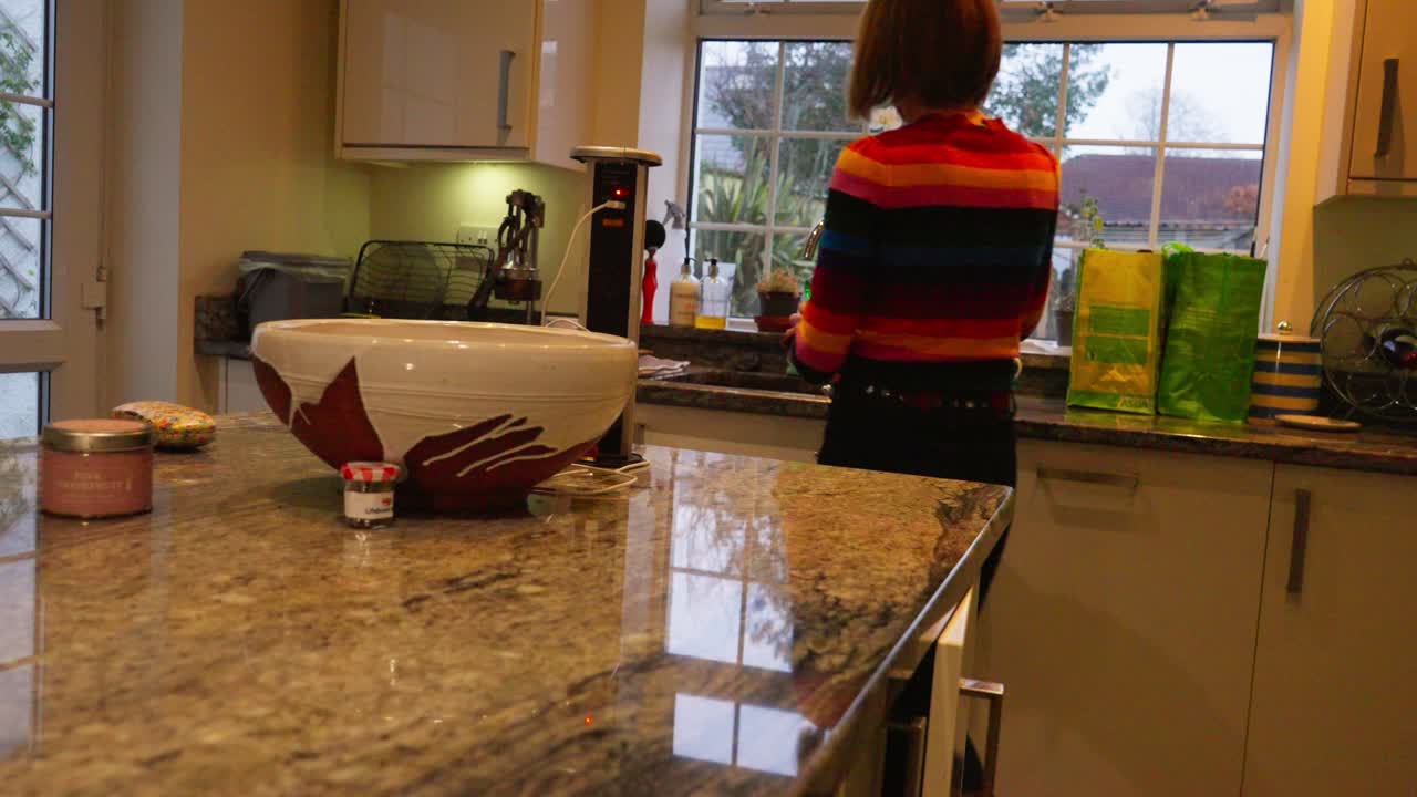 Woman grabbing green dish soap, home kitchen with marble countertop, slow motion