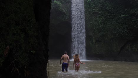 couple walking towards a magnificent waterfall in a lush jungle