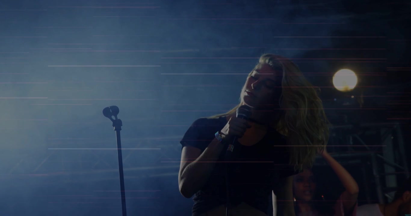 Lead vocalist stepping toward handheld mic singing for music tossing hair magenta lines streaking