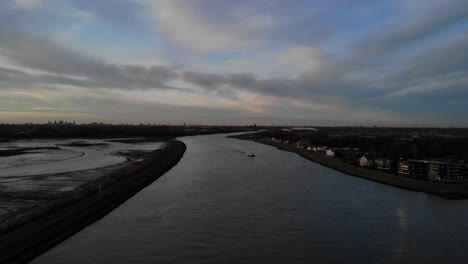 flying over noord river in netherlands at dusk as a boat sails passes