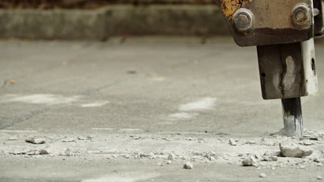 close-up of excavator hydraulic arm rock breaker working on concrete road with sound