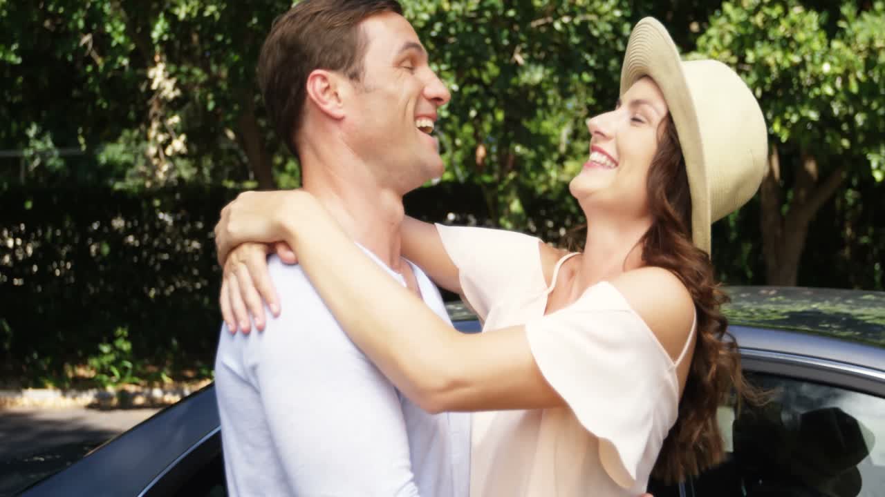 부부가 차 근처에서 서로 상호 작용하고 있습니다.