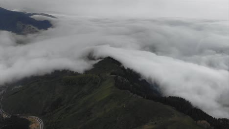 aerial above white clouds covered mountains in valley during rainy weather