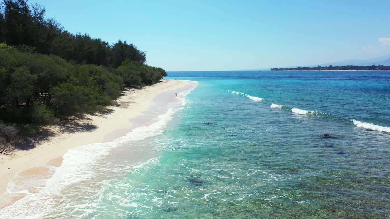무성한 녹색 식물과 맑은 바닷물이 있는 열대 해변의 아름다운 해안선에 부딪히는 얕은 파도
