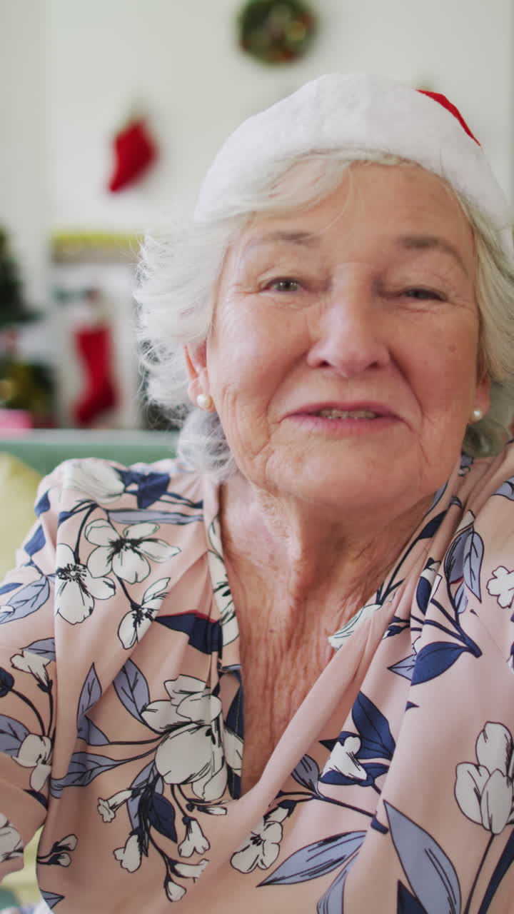 산타 해트 (santa hat) 의 고령 여성은 비디오 통화를 즐기며 축제 정신과 기술 사용을 구현합니다.