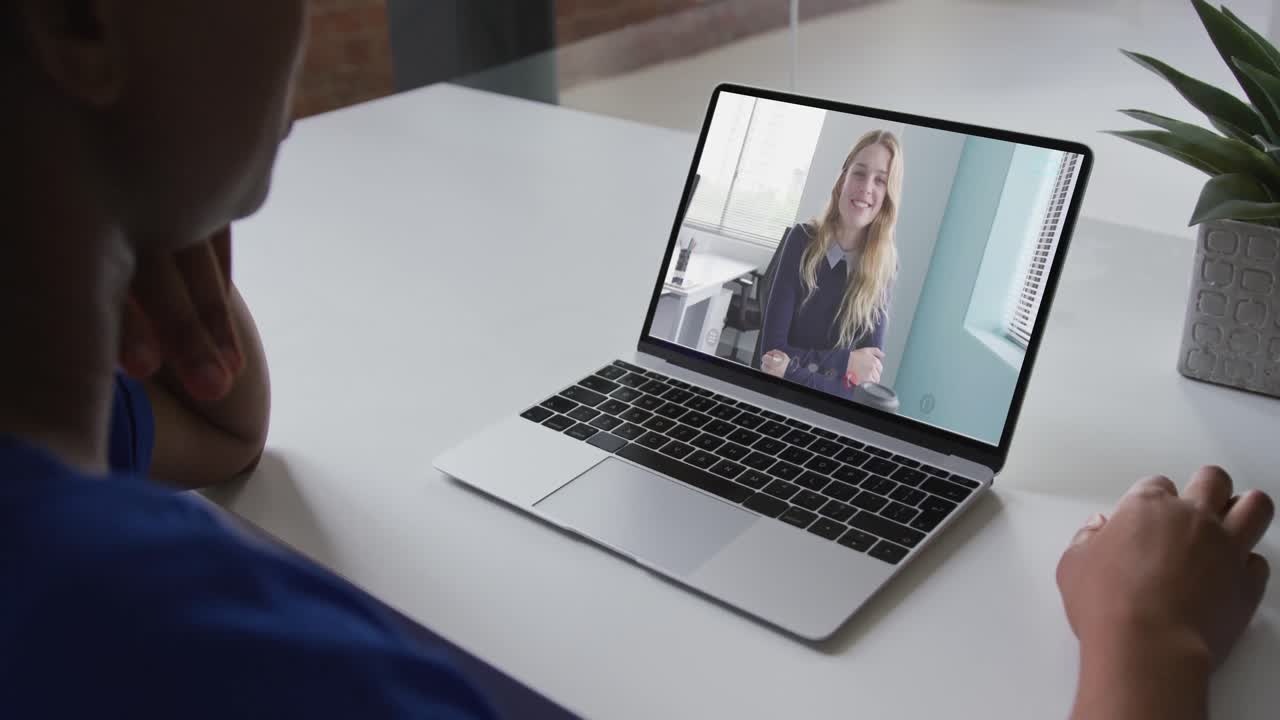 African american businesswoman sitting at desk using laptop having video call with female colleague