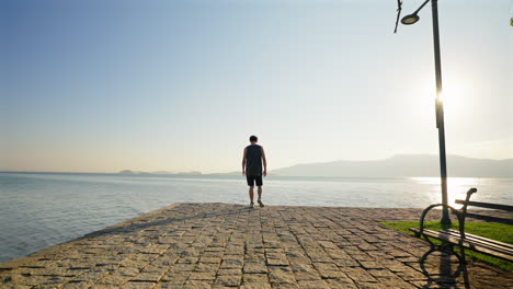 Lonely and sad man walking on waterfront at sunset