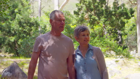 mature couple walking along forest path together