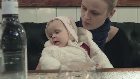 a woman sitting at the table with a baby daughter on her lap